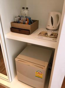 a small refrigerator under a shelf in a room at S Box Sukhumvit Hotel - SHA Extra Plus in Bangkok