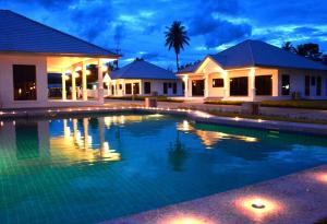 a swimming pool in front of a house at night at Mango Beach Resort Thailand in Ban Huai Yang