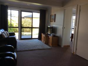 a living room with a couch and a tv and a door at Lakes Entrance Views in Lakes Entrance