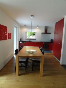eine Küche mit einem Holztisch und roten Schränken in der Unterkunft Chasa Felix Scuol in Scuol