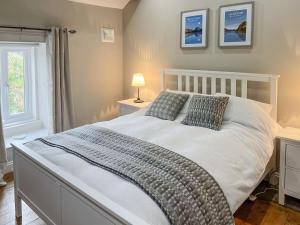 1 dormitorio con 1 cama blanca grande y 2 almohadas en Smithy Cottage en Keldhead
