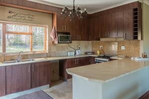 a kitchen with wooden cabinets and a counter top at Lekkerkry in Plettenberg Bay