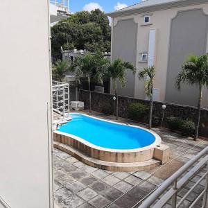 a large blue swimming pool in front of a building at Ocean Drive Studio, next to the Beach in Grand-Baie