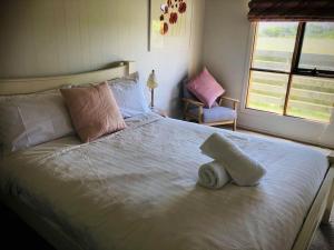 um quarto com uma grande cama branca com uma toalha em Peterborough Beach House em Peterborough
