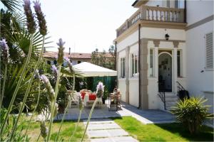 a white house with a patio and a white umbrella at Affittacamere Torre Dell'Arte in Torre del Lago Puccini