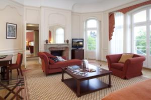 a living room with red chairs and a table at Le Domaine des Roches, Hotel & Spa in Briare