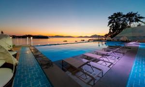 a pool with lounge chairs and the ocean at sunset at Arte Resort Spa & Pool Villa in Sacheon