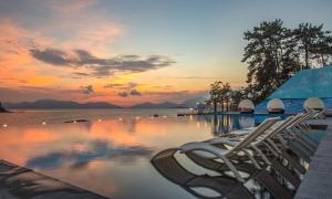 een zwembad met stoelen en de oceaan bij zonsondergang bij Arte Resort Spa & Pool Villa in Sacheon