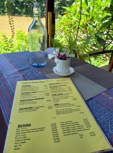 Mandala Ou Resort في Nongkhiaw: طاولة مع قائمة وزجاجة من النبيذ
