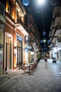 una strada vuota di notte con tavoli e sedie di Patras Casale a Patra