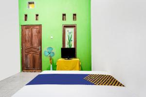 ein Schlafzimmer mit einem Bett, einem TV und einer Tür in der Unterkunft OYO 91747 Gamping Homestay Syariah in Gresik