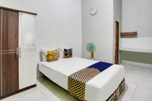 Schlafzimmer mit einem Bett mit gelben und blauen Kissen in der Unterkunft OYO 91747 Gamping Homestay Syariah in Gresik