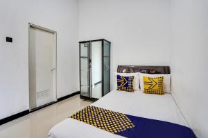 Schlafzimmer mit einem Bett mit gelben und blauen Kissen in der Unterkunft SPOT ON 91745 Rumah Kost Gresik Syariah in Gresik