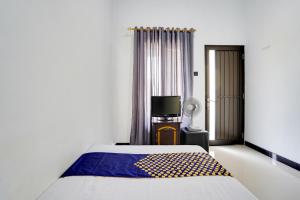 een slaapkamer met een bed en een tv. bij SPOT ON 91745 Rumah Kost Gresik Syariah in Gresik