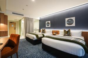 a hotel room with two beds and a desk at The Langlands Hotel in Invercargill