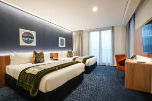 a hotel room with two beds and a desk at The Langlands Hotel in Invercargill