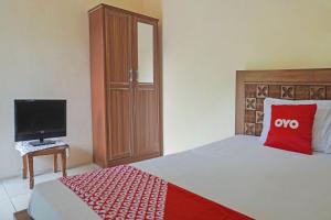 a bedroom with a bed with a red pillow and a tv at OYO 91762 Green Home Stay Syariah 