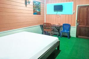 a bedroom with a bed and a table and a tv at OYO 91768 Hotel Tanjung Permai in Tanjungselor