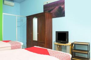 1 dormitorio con 2 camas, TV y una bañera de hidromasaje en OYO 91769 Wisma Harapan Baik, en Kupang