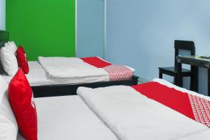2 camas con sábanas rojas y blancas en una habitación en OYO 91769 Wisma Harapan Baik, en Kupang