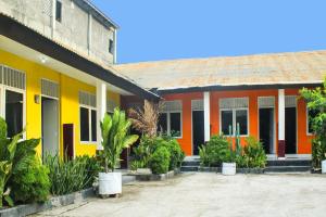 un edificio amarillo y naranja con plantas delante de él en OYO 91769 Wisma Harapan Baik, en Kupang