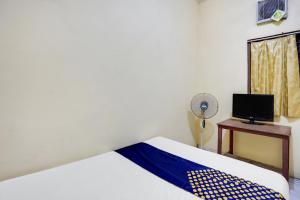 um quarto com uma cama e uma secretária com uma ventoinha em OYO 91774 Kost Nusantara Sidoarjo Syariah em Sidoarjo