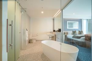 a bathroom with a bath tub and a bedroom at The Langlands Hotel in Invercargill
