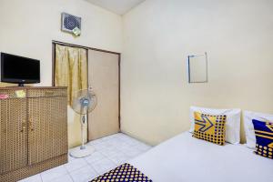 um quarto com uma cama, uma ventoinha e uma televisão em OYO 91774 Kost Nusantara Sidoarjo Syariah em Sidoarjo
