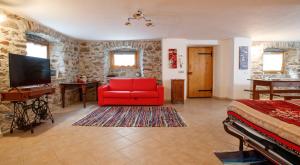 a living room with a red couch and a television at IL COMO' DELLA CIVETTA - Taverna “La Fenice” in Stazzona