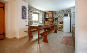 eine Küche mit einem Holztisch und einem Kühlschrank in der Unterkunft IL COMO' DELLA CIVETTA - Taverna “La Fenice” in Stazzona