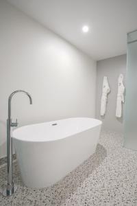 a white bath tub in a bathroom with a tile floor at The Langlands Hotel in Invercargill