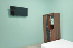 Cette chambre comprend un lit et une télévision murale. dans l'établissement SPOT ON 91791 Homestay Surya Syariah, à Tarakan