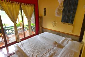 a bedroom with a bed and a large window at Mandala Ou Resort in Nongkhiaw