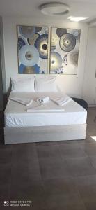 a white bed in a room with paintings on the wall at Ioannas Endless Blue Apartment in Ierapetra