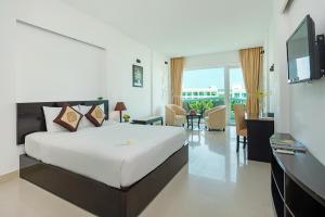 a bedroom with a large bed and a living room at The Sailing Bay Beach Resort in Mui Ne