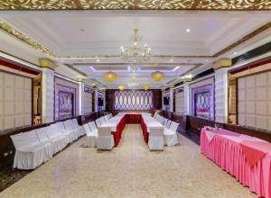a banquet hall with white and pink tables and chairs at Hotel Yatrik in Jhānsi