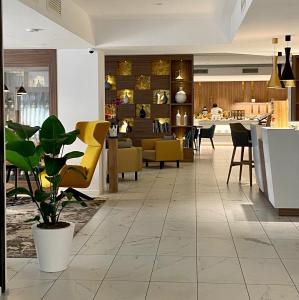 a lobby with yellow chairs and a restaurant at Solho Hotel in Bardolino