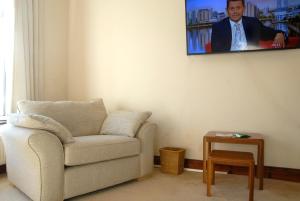 a living room with a chair and a tv on the wall at Seashells Cottage in Gorleston-on-Sea