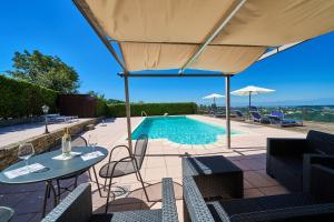 a swimming pool with a table and chairs and an umbrella at Cascina Filipot in Cerretto Langhe