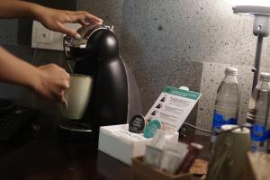 a person is making a cup of coffee in a coffeeicterotent at ARTOTEL Haniman Ubud in Ubud