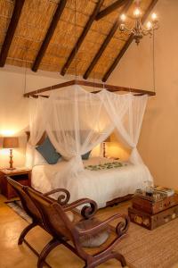 1 dormitorio con cama con dosel y silla en Mvuradona Safari Lodge en Marloth Park
