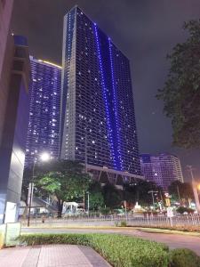 um edifício alto com luzes azuis à noite em Tropical Home at SMDC Air Residences Makati em Manila