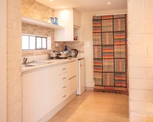 a white kitchen with a sink and a window at Nature on the HIll in Harare