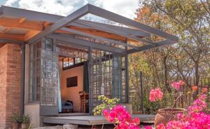 a screened in porch of a house with pink flowers at Nature on the HIll in Harare