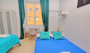ein Schlafzimmer mit zwei Betten mit blauer Bettwäsche und einem Fenster in der Unterkunft Guests House Mercado Malaga in Málaga
