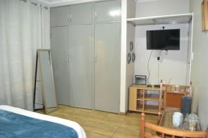 センチュリオンにあるGreen Grove Villaのベッドルーム1室(ベッド1台、壁にテレビ付)