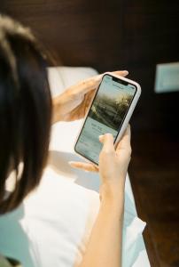 a woman holding up a cell phone in her hand at ARTOTEL Haniman Ubud in Ubud