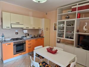 una cocina con armarios naranjas y una mesa y sillas blancas. en La casina sul lago, en Arezzo 11 fotos más
