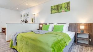 a bedroom with a large bed with green sheets at Hotel Stadt Mühlhausen in Mühlhausen