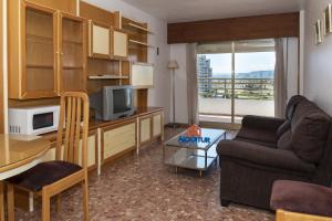 ein Wohnzimmer mit einem TV, einem Sofa und einem Tisch in der Unterkunft Nereo, 10º-45 in Cullera